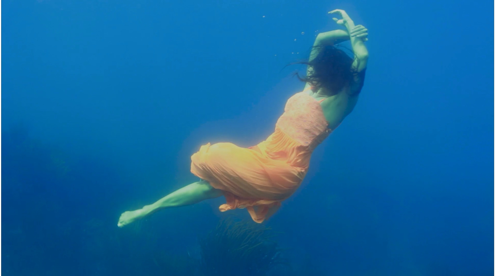 Woman swimming underwater in orange dress
