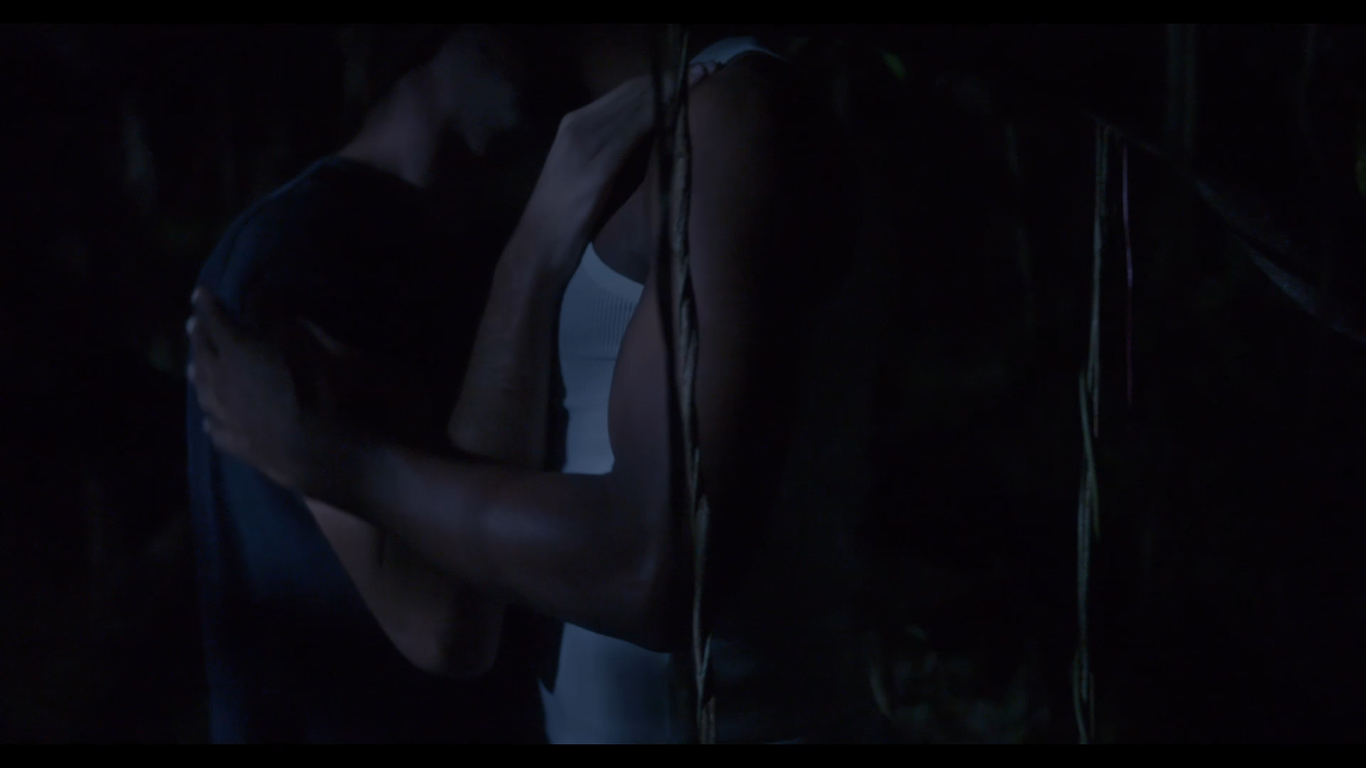 Two men embrace in a dark forest
